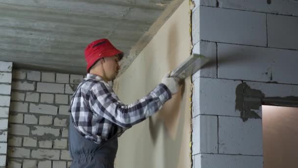 Bauarbeiter nivelliert Putz mit Lineal auf Porenbetonsteinwand — Stockvideo