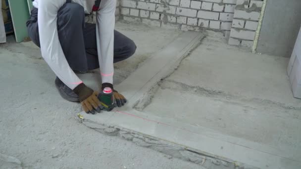 Stavební dělník dělá opatření s laserovou nivelací na staveništi — Stock video