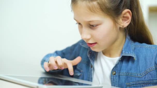 청바지에 어린 소녀의 태블릿에 게임을 착용 — 비디오