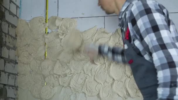 Costruttore in usura da lavoro mettendo intonaco su muro in cemento armato — Video Stock