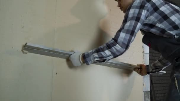 Builder leveling plaster on aerated concrete block wall with construction ruler — Stock Video