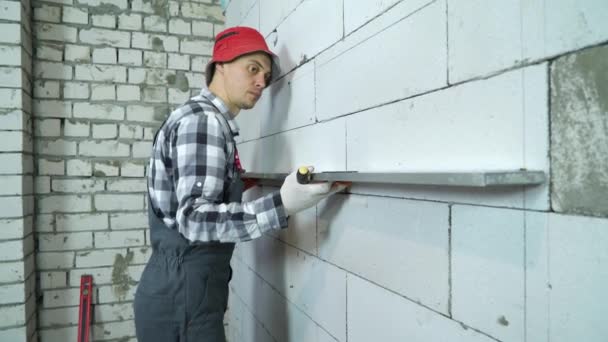 Builder applies construction ruler to aerated concrete wall to check its marking — Stock Video