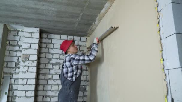 Plasterer smoothing plaster on interior wall with construction ruler — Stock Video