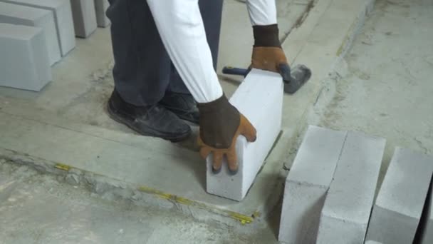 Manos constructor tomando bloque de hormigón aireado y colocándolo sobre cimientos de cemento — Vídeos de Stock
