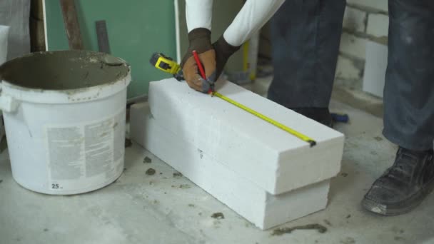 Constructor mide bloque de hormigón aireado con cinta métrica y regla de esquina — Vídeo de stock