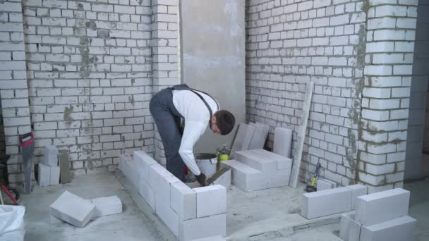 Constructeur met une solution adhésive sur les côtés du bloc de béton aéré avec spatule — Video