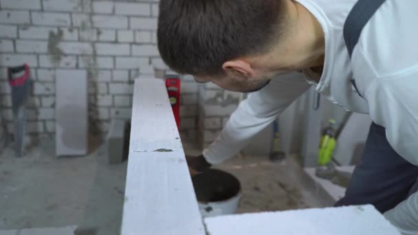 Trabajador de la construcción comprobando la uniformidad de la pared de hormigón aireado con nivel de burbuja — Vídeos de Stock