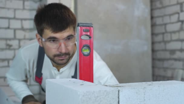 Trabalhador da construção turva verificando uniformidade da parede com nível de bolha — Vídeo de Stock