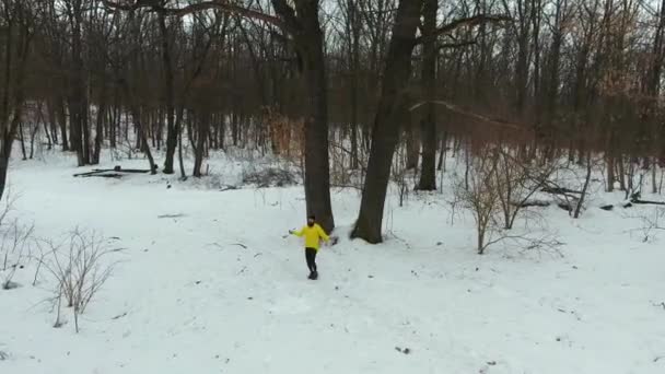 Aérea de deportista en abrigo amarillo haciendo ejercicio con cuerda de salto en bosque de invierno — Vídeo de stock