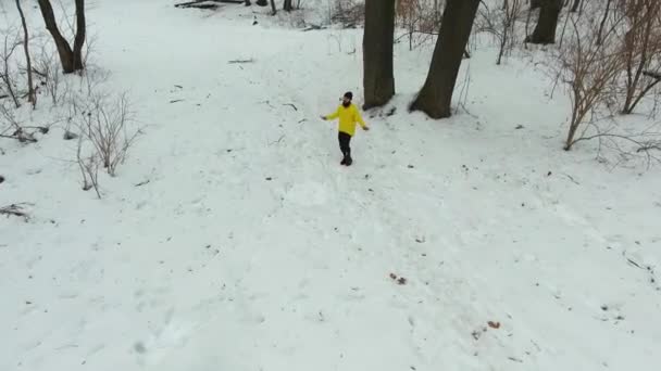 Повітряна бородата людина в жовтому пальто стрибає з пропускаючим мотузкою в зимовому лісі — стокове відео