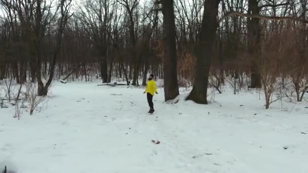 Антенна бородатого спортсмена в желтом пальто, прыгающего с веревкой в зимнем лесу — стоковое видео