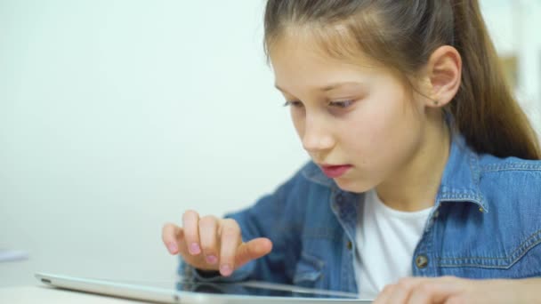Портрет возбужденной маленькой девочки, играющей в онлайн игры на планшете — стоковое видео