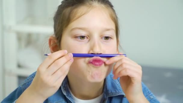 Écolière avoir amusant et faire des visages avec crayon de couleur comme moustache — Video