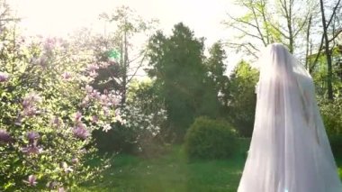 arkadan güneşli çiçek bahçe yavaş çekimde yürürken gelin görünüşü
