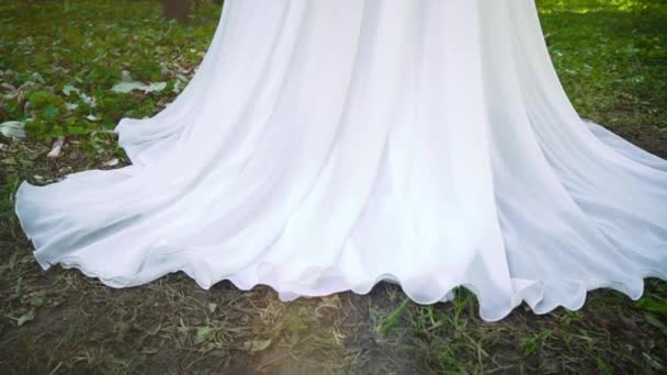 Pedestal shot of bride in long white dress in blooming garden — Stock Video