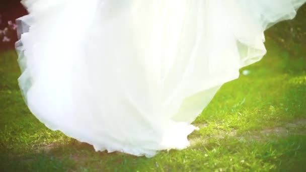 Низкий снимок женщины в свадебном платье разворачивается в зеленом саду в замедленной съемке — стоковое видео
