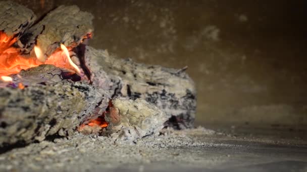 Closeup pan shot of wood logs burning and breaking in fireplace in slow motion — Stock Video