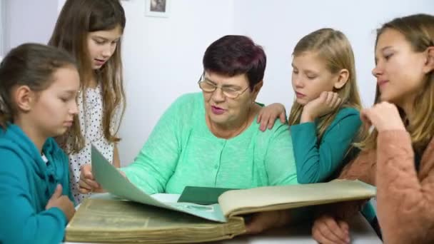 Abuela mostrando viejo álbum de fotos a sus cuatro nietas — Vídeo de stock