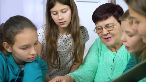 Девушки смотрят старый фотоальбом со своей бабушкой — стоковое видео