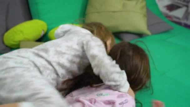 Zwei kleine Mädchen kämpfen auf dem Sofa um Spaß — Stockvideo