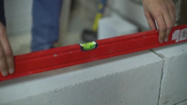 Mains de constructeur mettre le niveau de bulle sur le mur nouvellement construit pour vérifier sa régularité — Video