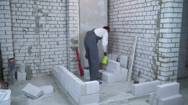 Constructor masculino joven bloque humectante con rociador de agua antes de ponerlo — Vídeo de stock