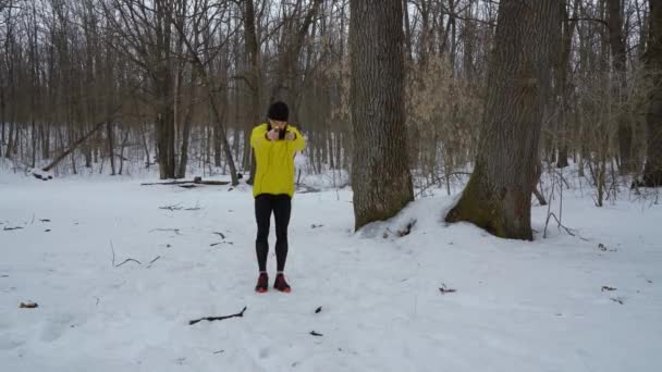 Hombre de deportes en abrigo amarillo saltar con cuerda en el bosque de invierno con espacio libre — Vídeos de Stock