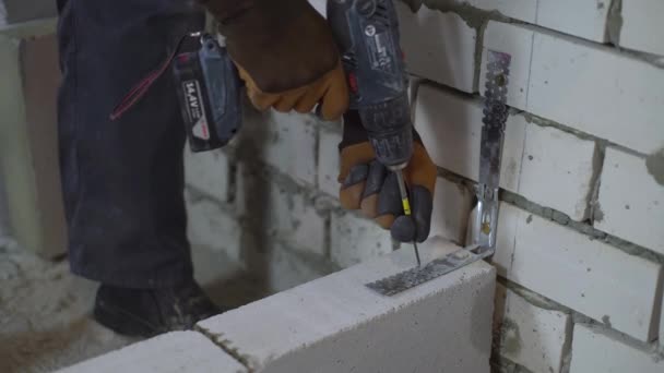 Vista de mãos construtor fixação junção braçadeira para paredes de tijolo com broca elétrica — Vídeo de Stock