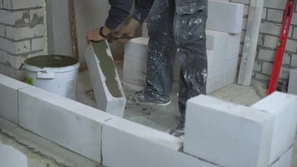 Nízké záběr tvůrce uvedení Malty na pórobetonu betonového bloku s špachtlí — Stock video