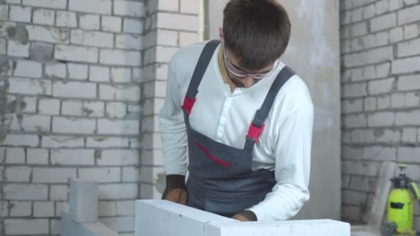 Young male builder checking evenness of aerated concrete wall — Stock Video