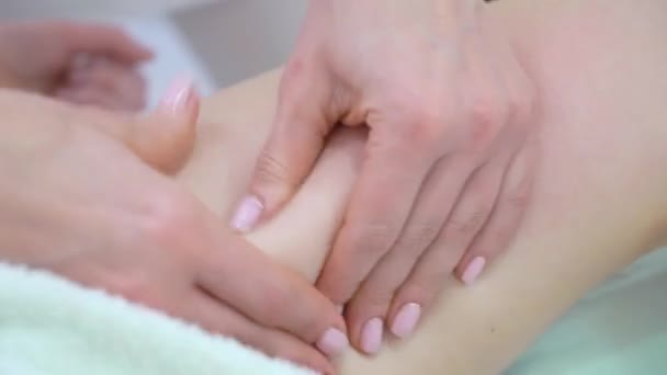 Крупним планом жіночі руки масажують молоді стегна жінки в спа-салоні — стокове відео