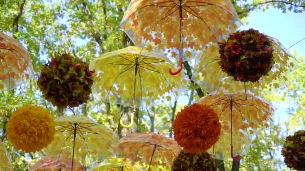 Paraguas y bolas brillantes de color naranja y amarillo que cuelgan y se mueven en el viento — Vídeos de Stock