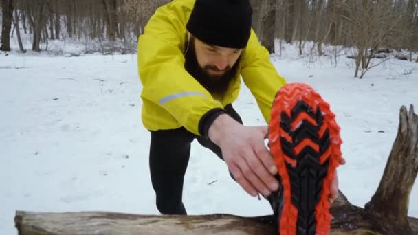 Atlético ajuste hombre estiramiento piernas antes de correr en invierno bosque — Vídeos de Stock