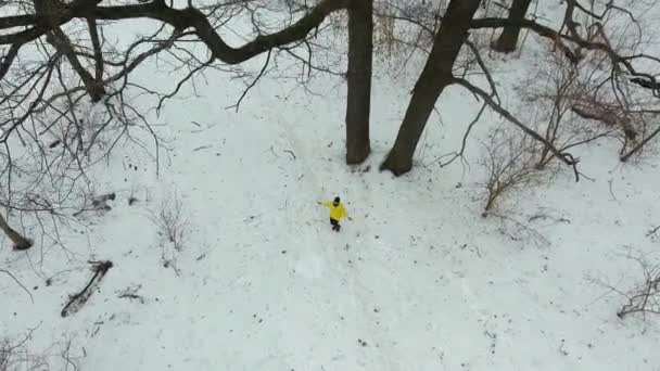 Aérea de atleta barbudo en abrigo amarillo saltando con cuerda en bosque de invierno — Vídeos de Stock