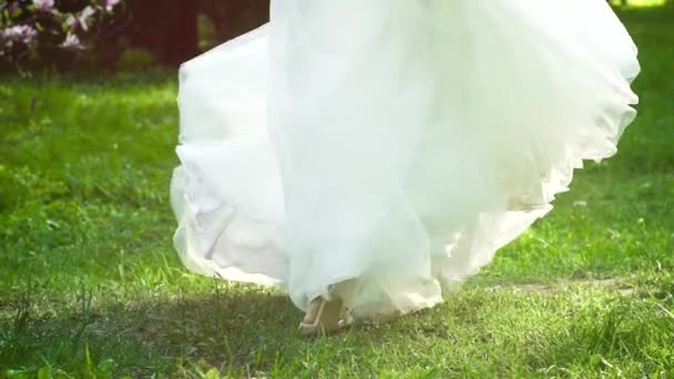 Низький знімок нареченої у весільній сукні, що обертається навколо зеленої трави в повільному русі — стокове відео