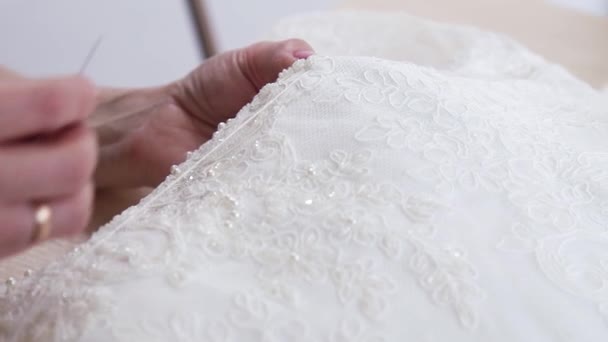 Крупный план рук швеи, сшивающих бусины в элегантную кружевную ткань — стоковое видео