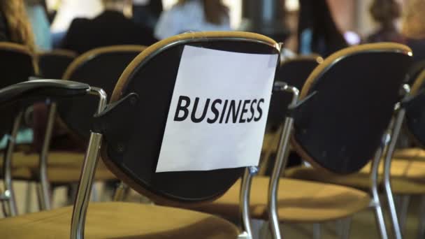 Business note stuck to chair in meeting room with blurred people on background — Stock Video