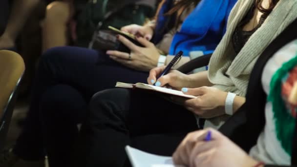 Обрізаний вид жінок, які сидять на діловій зустрічі і роблять нотатки в блокнотах — стокове відео