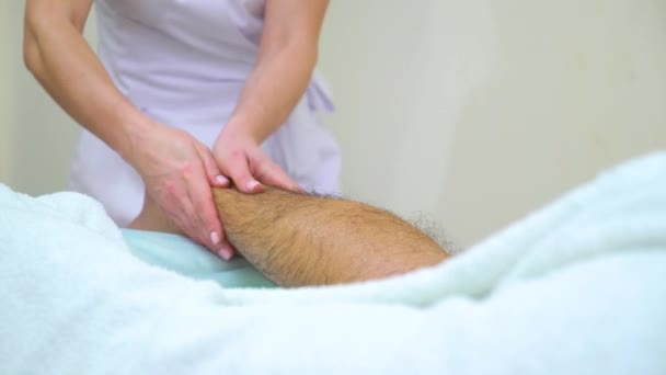 Tilt up di massaggiatore femminile massaggiare peloso stinco di giovane uomo in spa salone — Video Stock