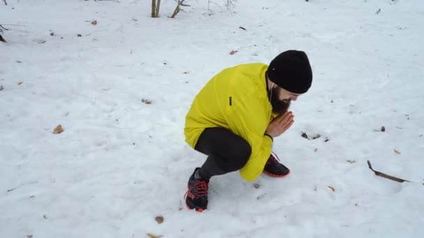 Низкий кадр мужчины спортивного человека разогревается перед бегом в зимнем лесу — стоковое видео