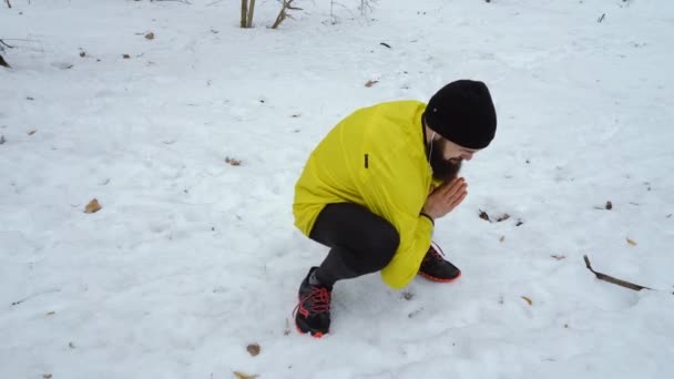 Low shot of male sports man warming up before running in winter forest — Stock Video