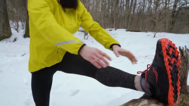 Tiro de arco del hombre atlético ajuste estirando las piernas antes de correr en el bosque de invierno — Vídeos de Stock