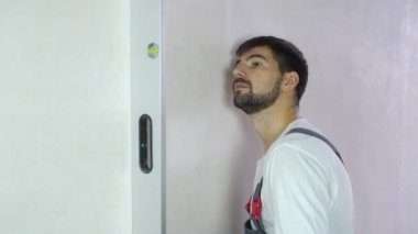 Genç sakallı Oluşturucu kabarcık seviyesi ile yeni duvar kalitesini kontrol