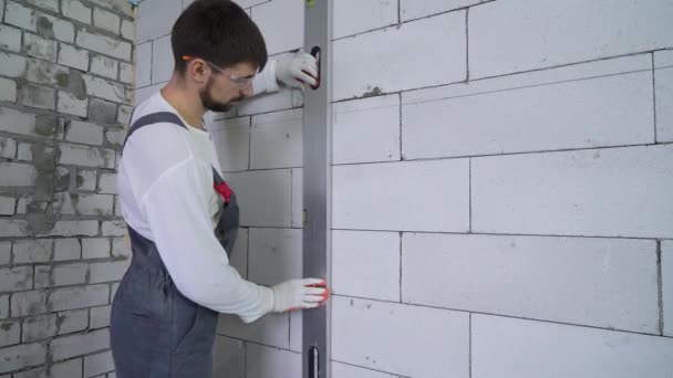 Bouwer tekening een lijn op de muur volgens laserstraal niveau — Stockvideo