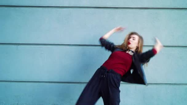 Seksowna kobieta wykonujący nowoczesny taniec w pobliżu szarej teksturowanej ścianie na zewnątrz — Wideo stockowe
