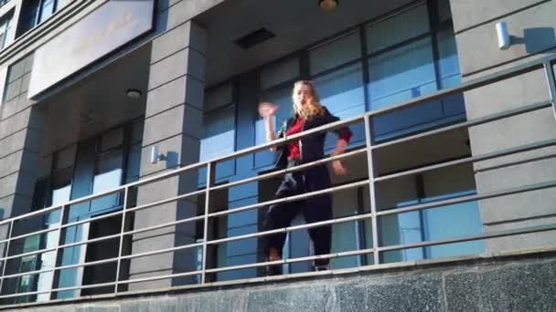 Belle femme blonde dansant près des balustrades en métal sur la rue de la ville — Video