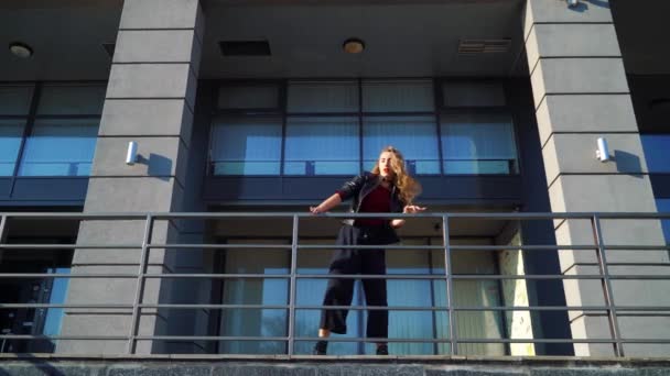 Mujer rubia bailarina callejera realizando cerca de barandillas metálicas de edificio moderno — Vídeos de Stock