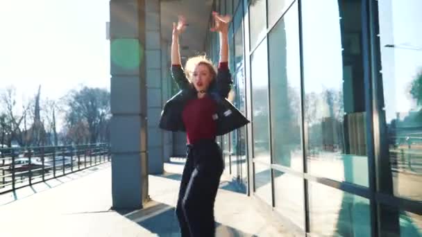 Rubia bailarina callejera actuando en la luz del sol cerca de edificio moderno — Vídeo de stock