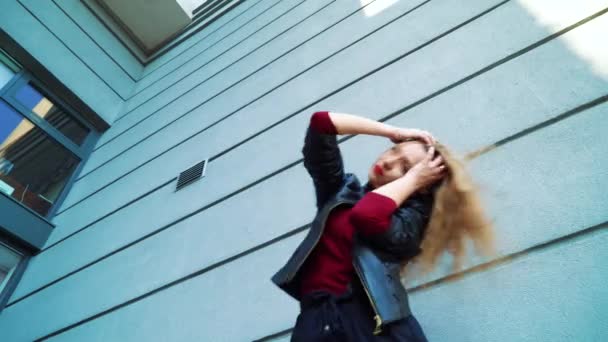 Basso angolo colpo di ballerina di strada femminile esibendosi vicino edificio moderno al tramonto — Video Stock