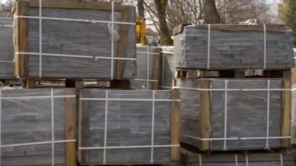 Stacks of paving stones wrapped in film laying on ground outdoors — Stock Video